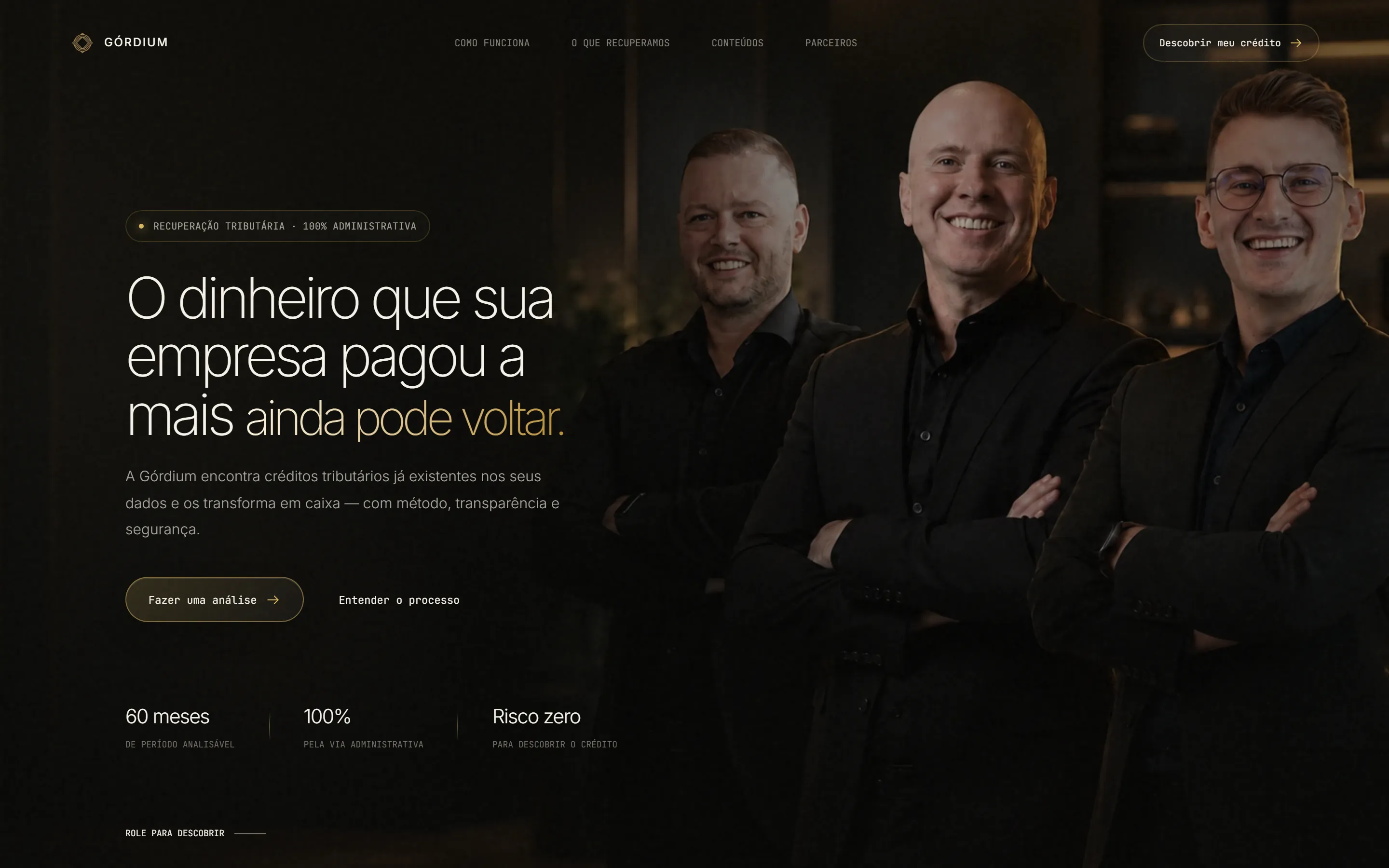 Topo do site da Górdium no desktop: fundo escuro, título “O dinheiro que sua empresa pagou a mais ainda pode voltar.” com as últimas palavras em dourado, botões “Fazer uma análise” e “Entender o processo”, três indicadores e a foto de três homens de braços cruzados à direita.